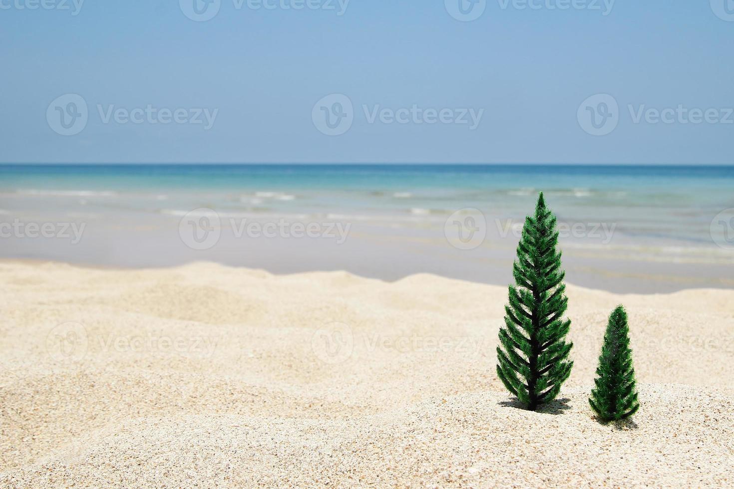 Two artificial Christmas trees on a sandy beach on the background of blue sea and sky, with copy space. photo