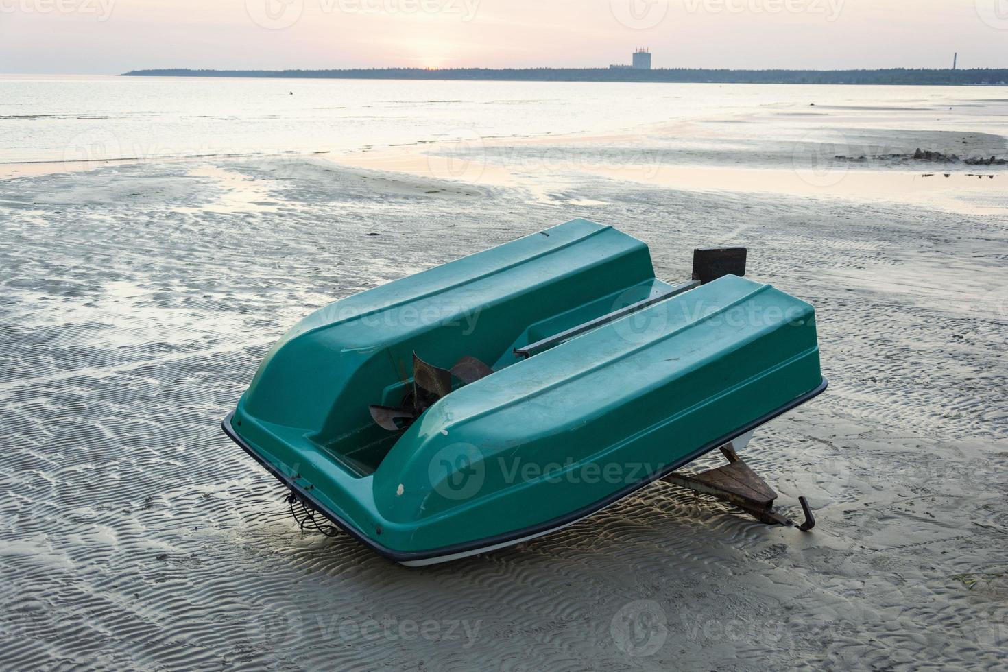 un viejo bote de plástico invertido en la orilla de la bahía del mar, un viejo catamarán, una hélice foto