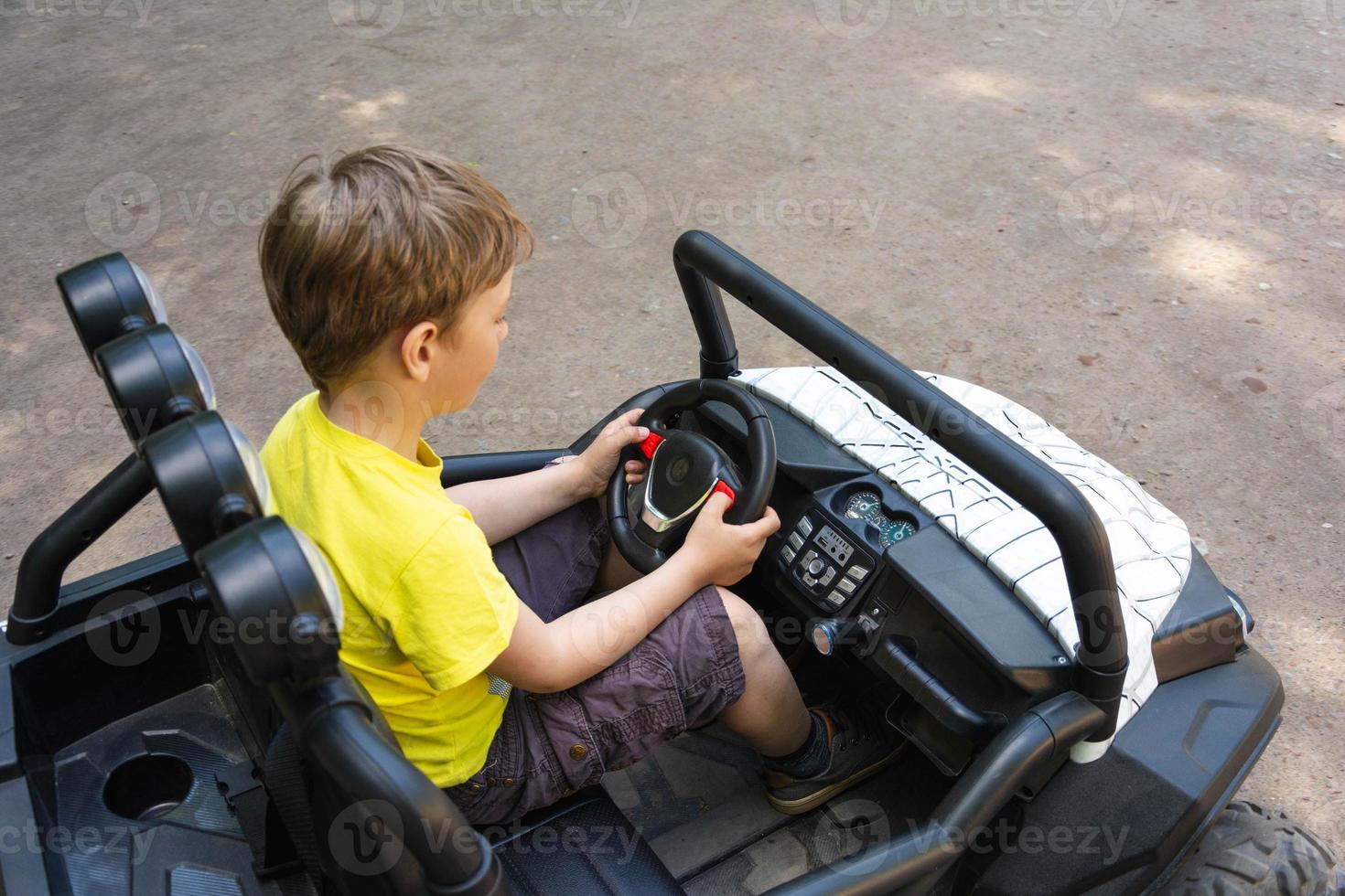cute european boy rides a children's car in the park, children's rides, park entertainment, children's electric car photo
