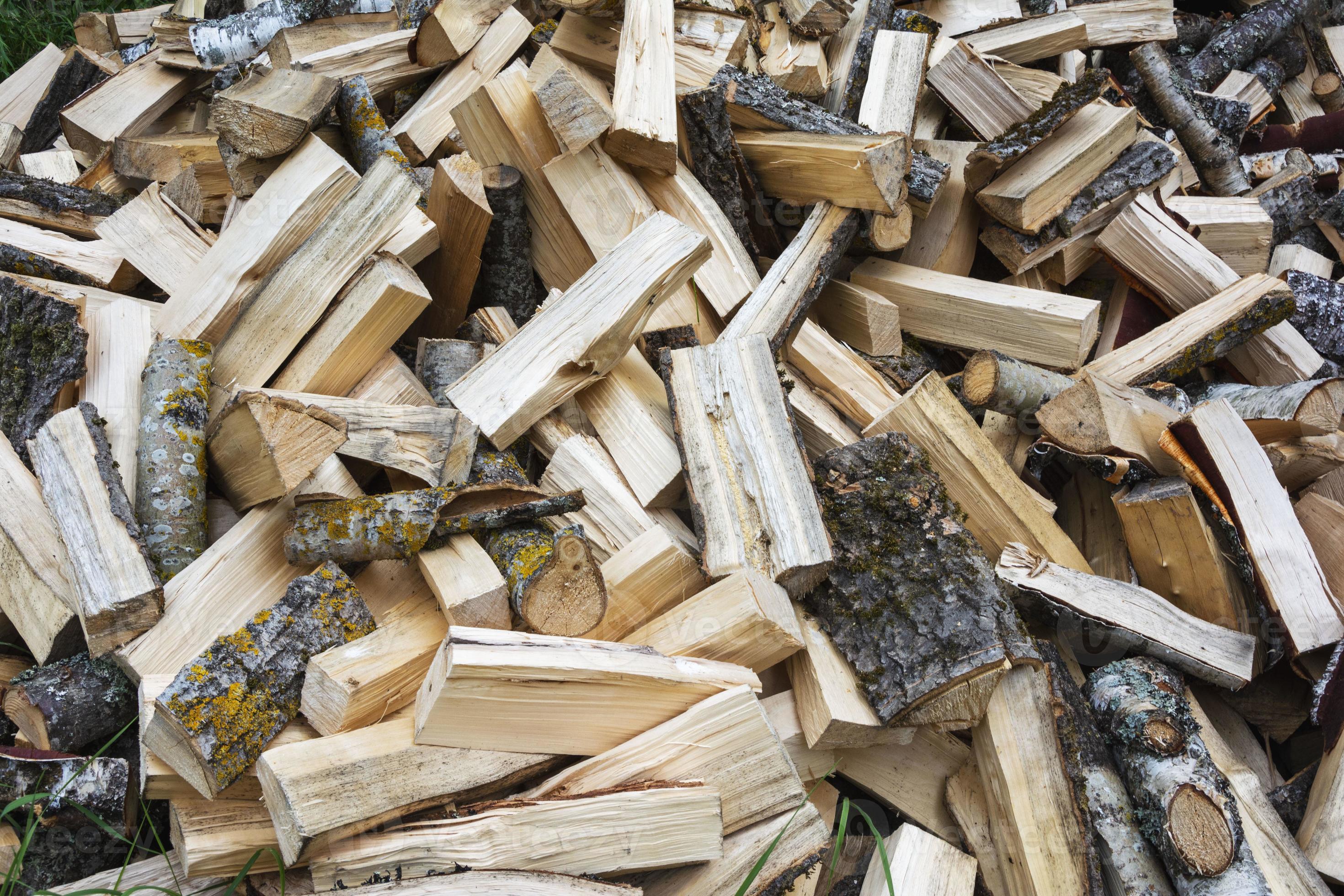 a pile of chopped birch wood is poured out on the grass in front of the