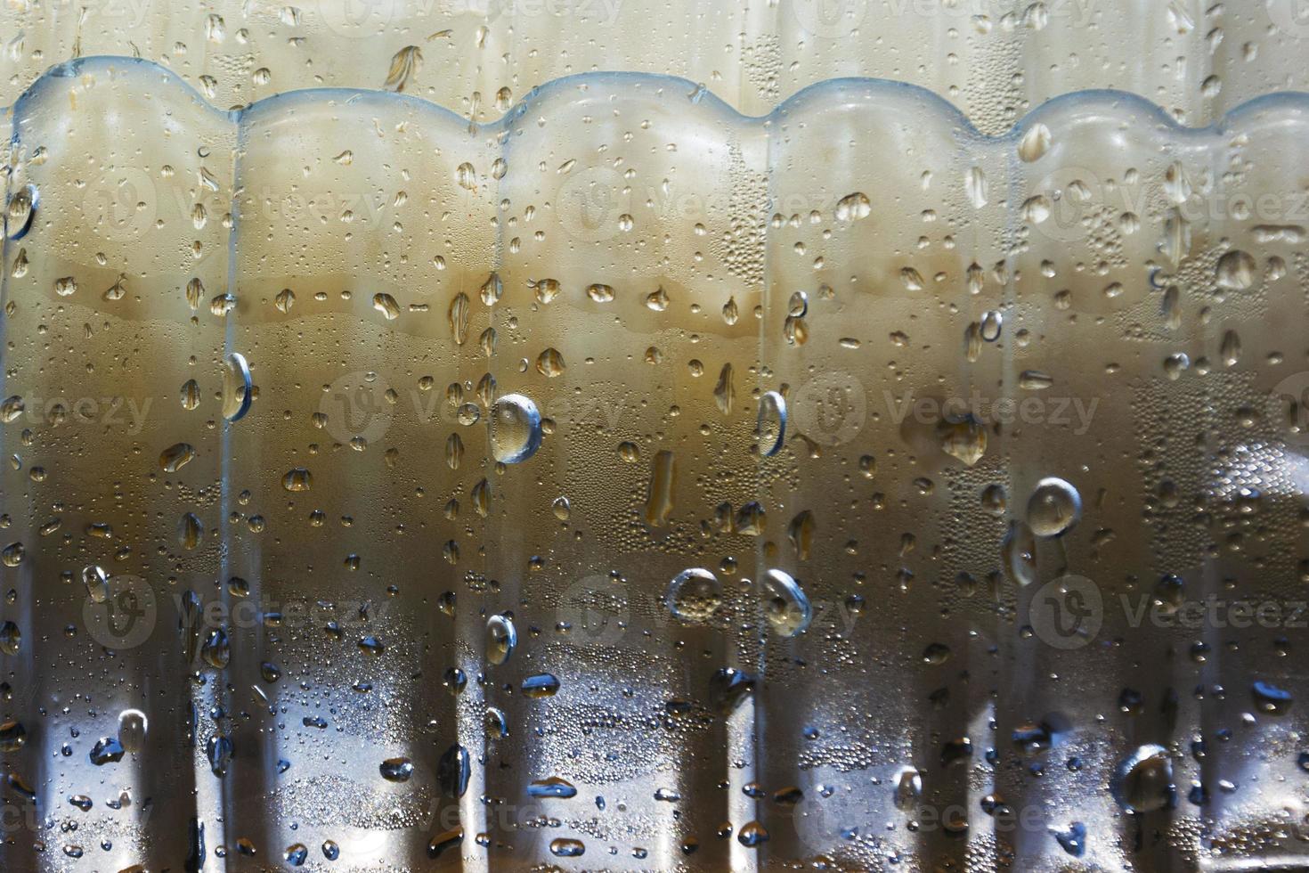 drops of condensate drain from a cold bottle of drinking water on a hot day, abstract background with water and drops photo