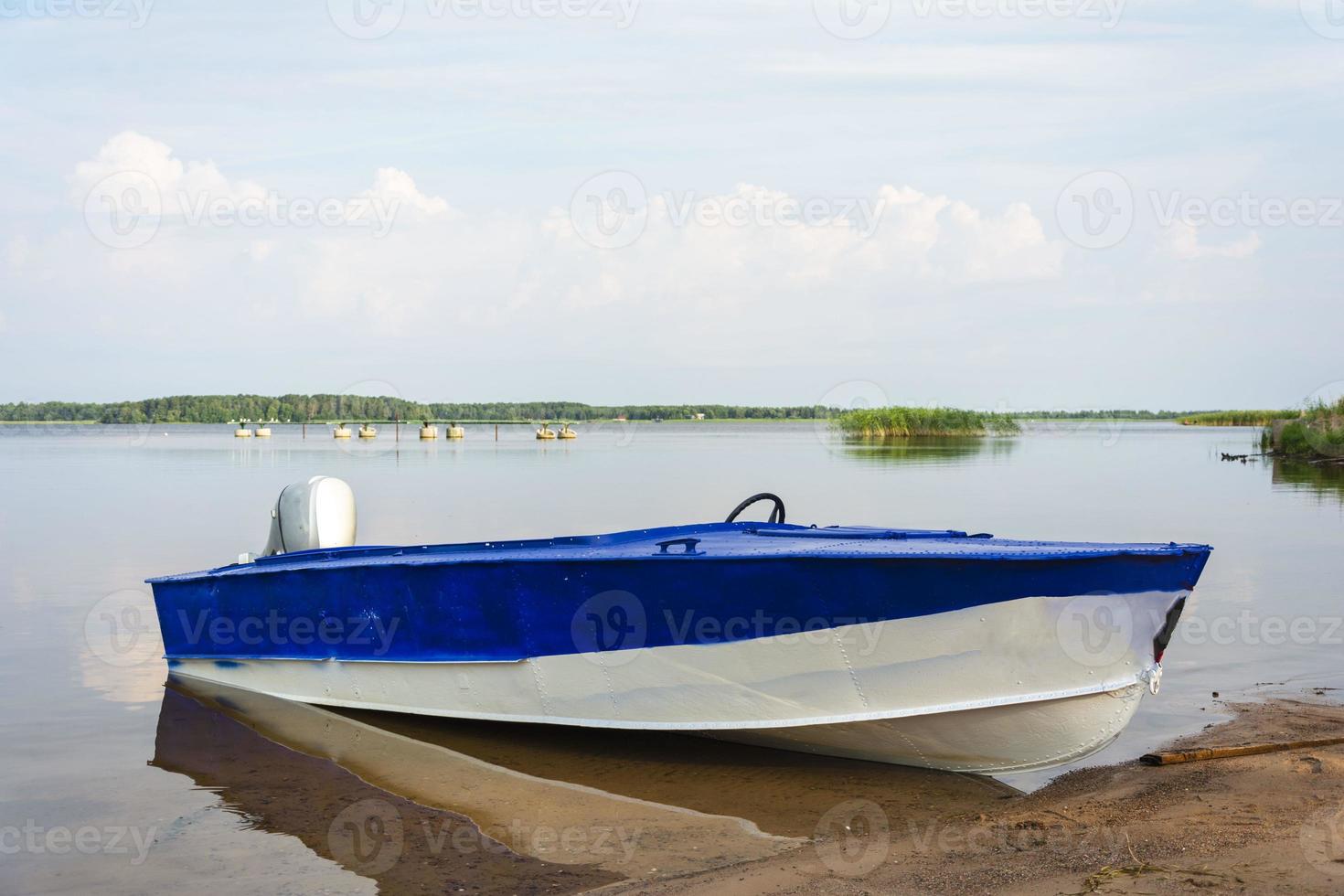 Aluminum blue fishing boat with a motor near the lake shore, fishing, tourism, active recreation, lifestyle. Background of nature. Natural landscape photo