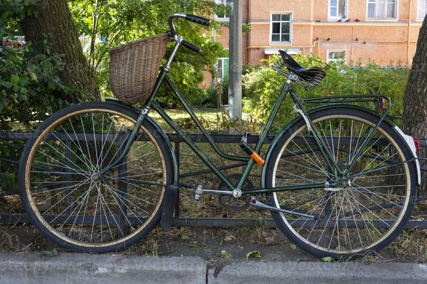 elegante bicicleta retro vintage verde con cesta de mimbre estacionada en la ciudad foto