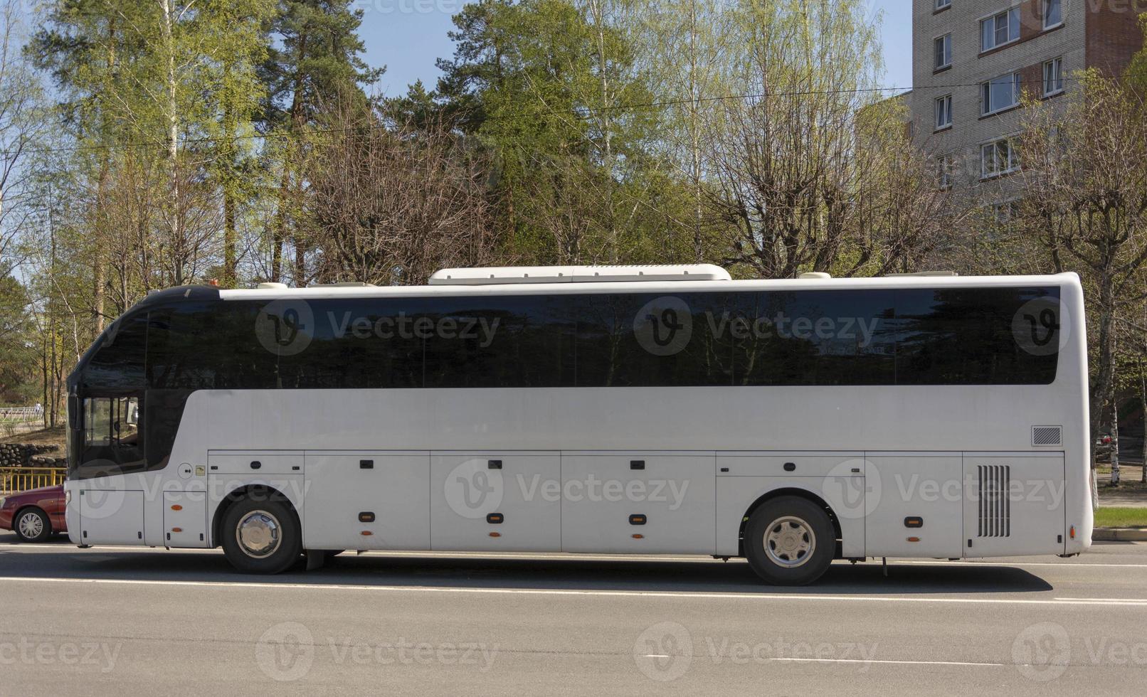 White tourist bus standing at a traffic light in the city photo