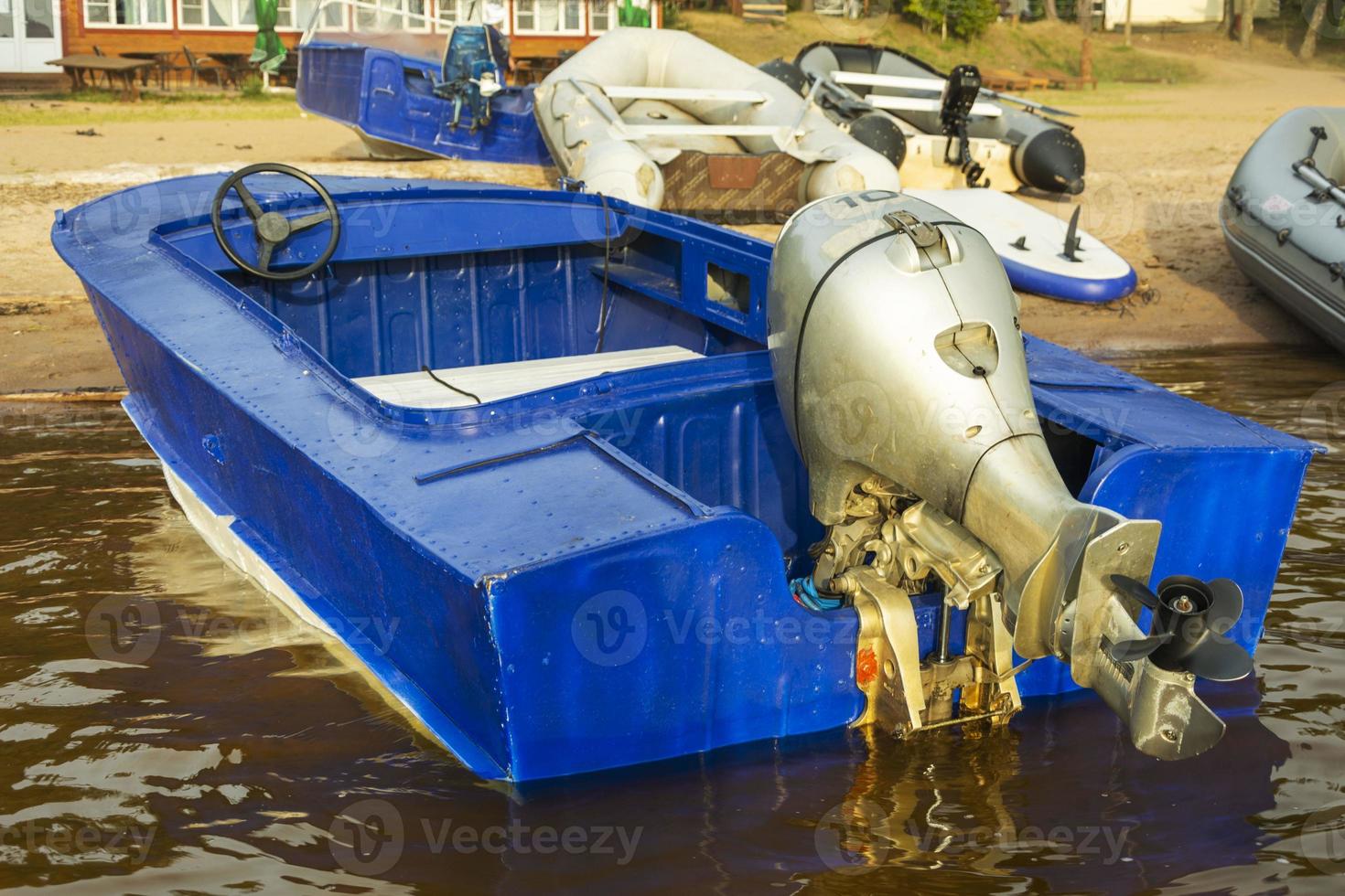 Aluminum blue fishing boat with a motor near the lake shore, fishing, tourism, active recreation, lifestyle. Background of nature. Natural landscape photo