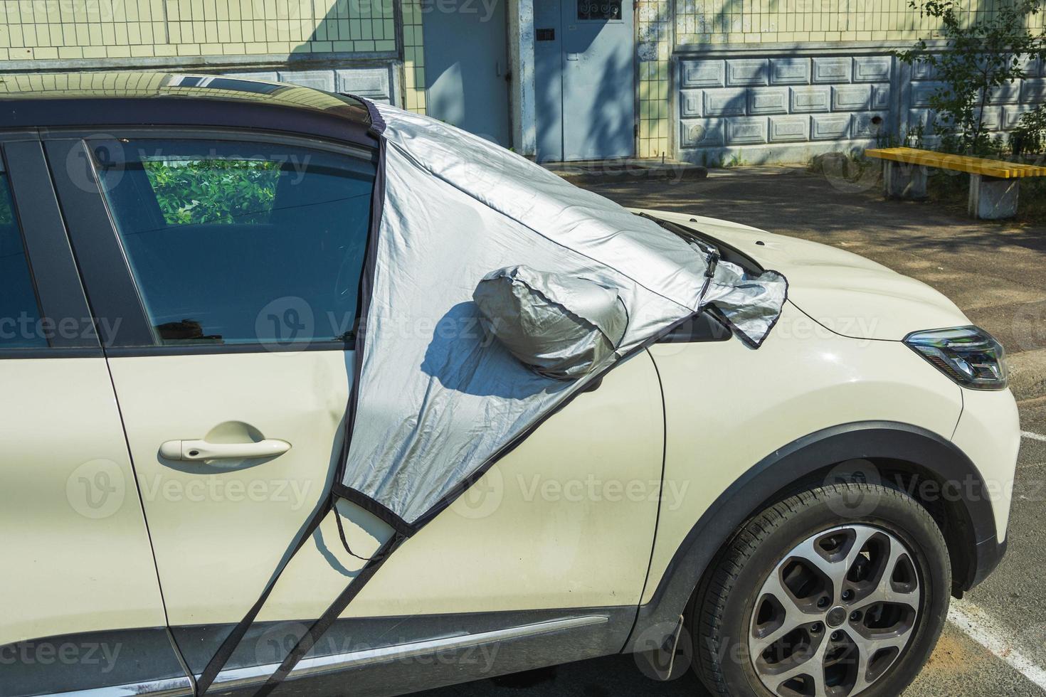 un automóvil en un estacionamiento con un parabrisas cubierto con un reflector de protección solar en el exterior foto