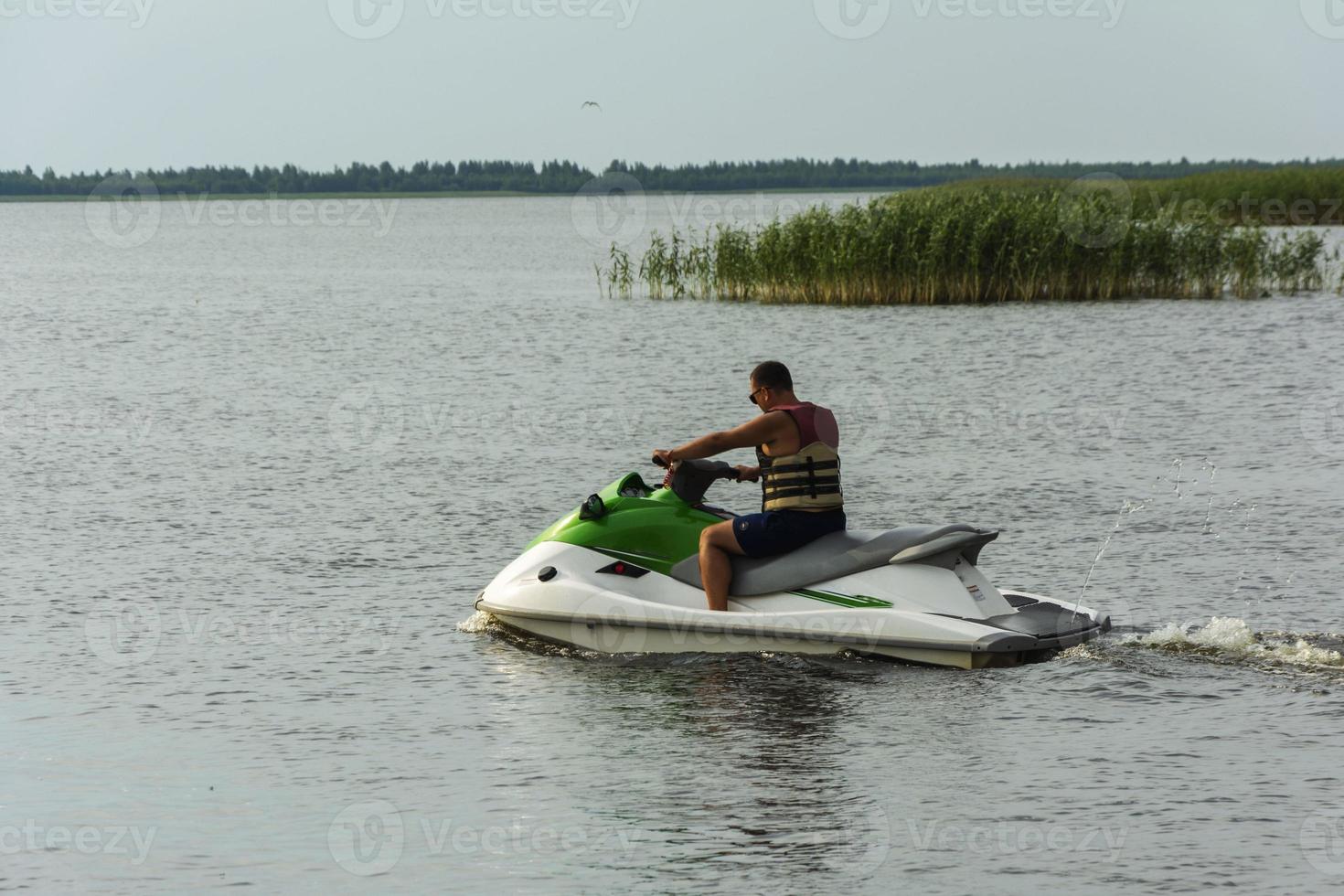 un joven monta una moto de agua en el lago, un hombre monta una moto de agua, estilo de vida activo, verano, agua, calor, vacaciones foto