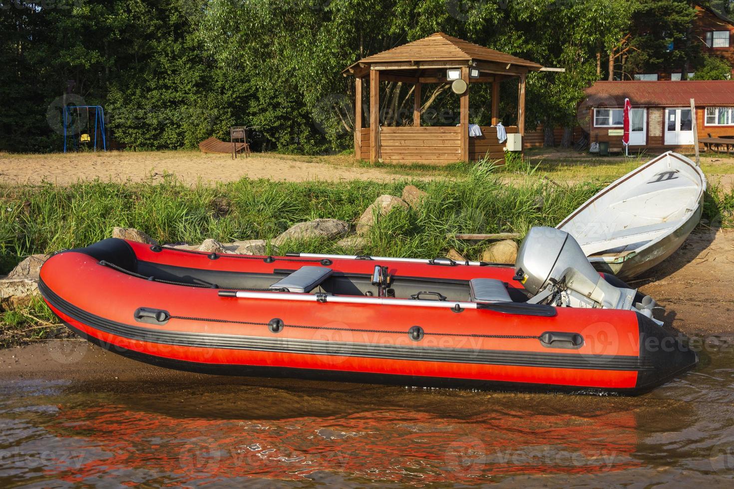 Red inflatable rubber boat with a motor near the lake shore, fishing, tourism, active recreation photo