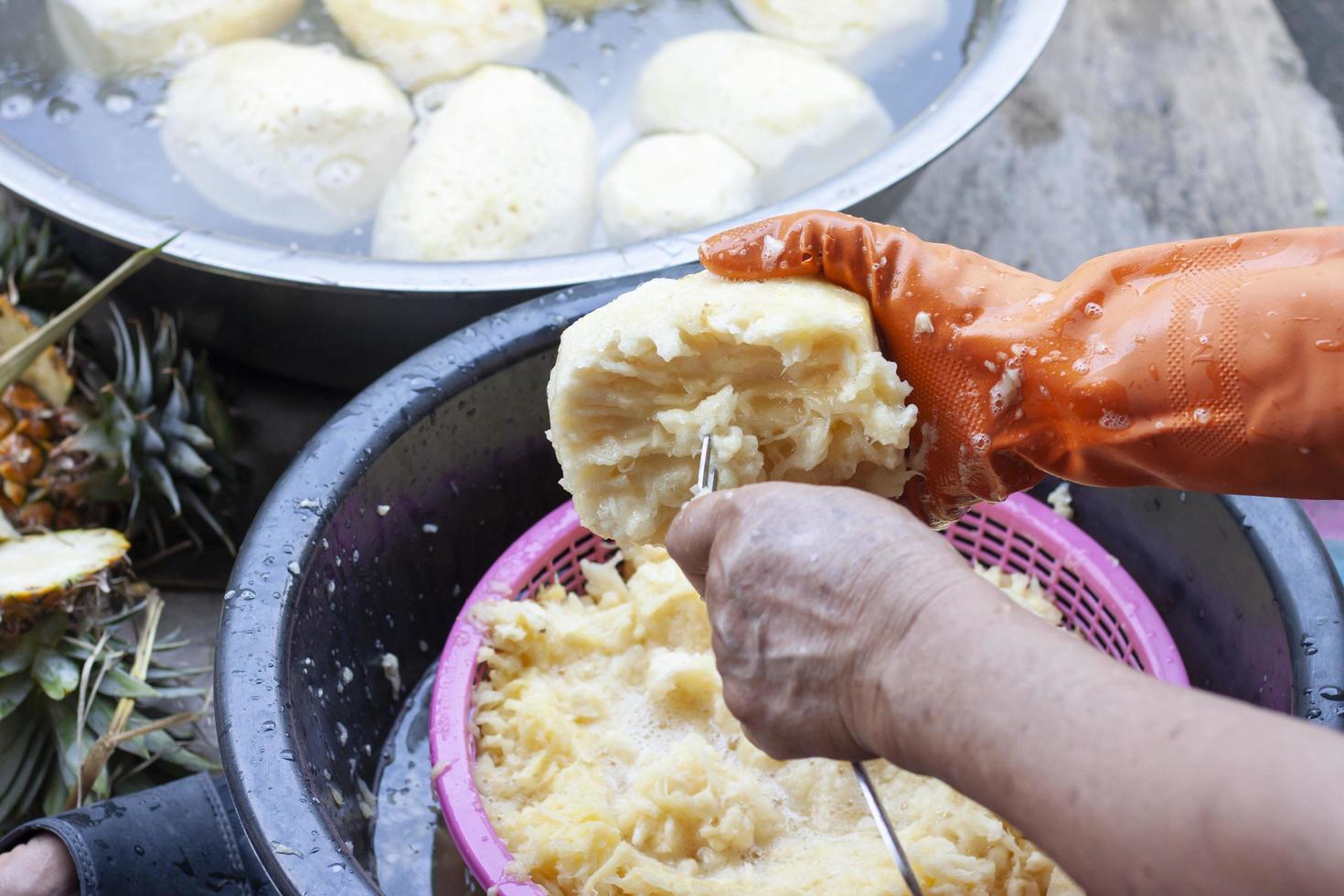 A woman's hand held a fork to grate the pineapple into small pieces to prepare to be processed into a stirring pineapple. photo