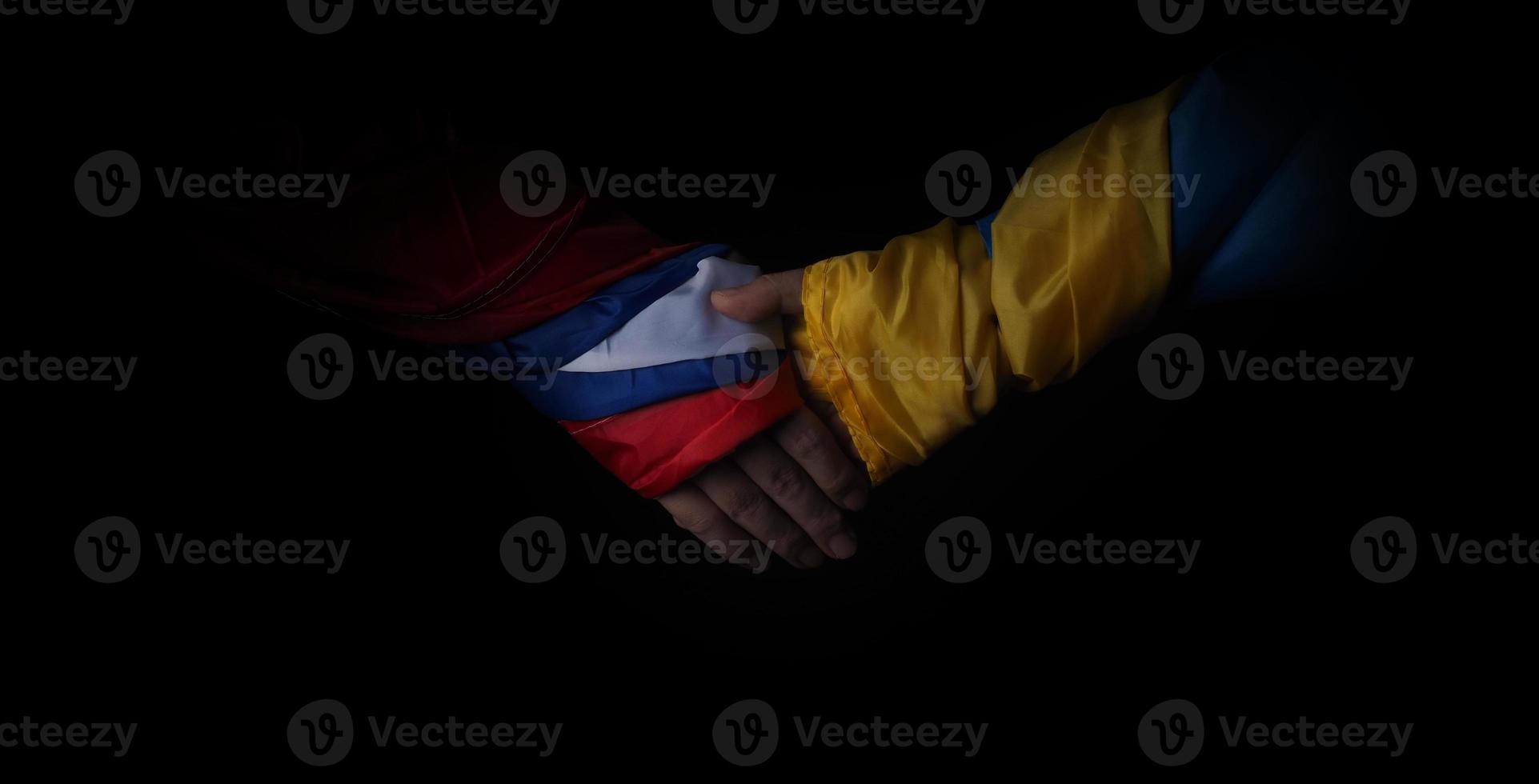 Russian flag and Ukraine flag in hands showing symbol of struggle war photo