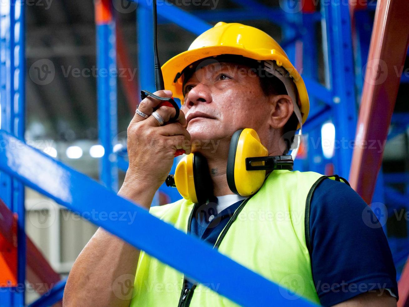 Foreman male business person people young adult yellow hardhat helmet safety speak talk takie wakie discussion warehouse terminal factory architect technology construction headwear supervisor concept photo