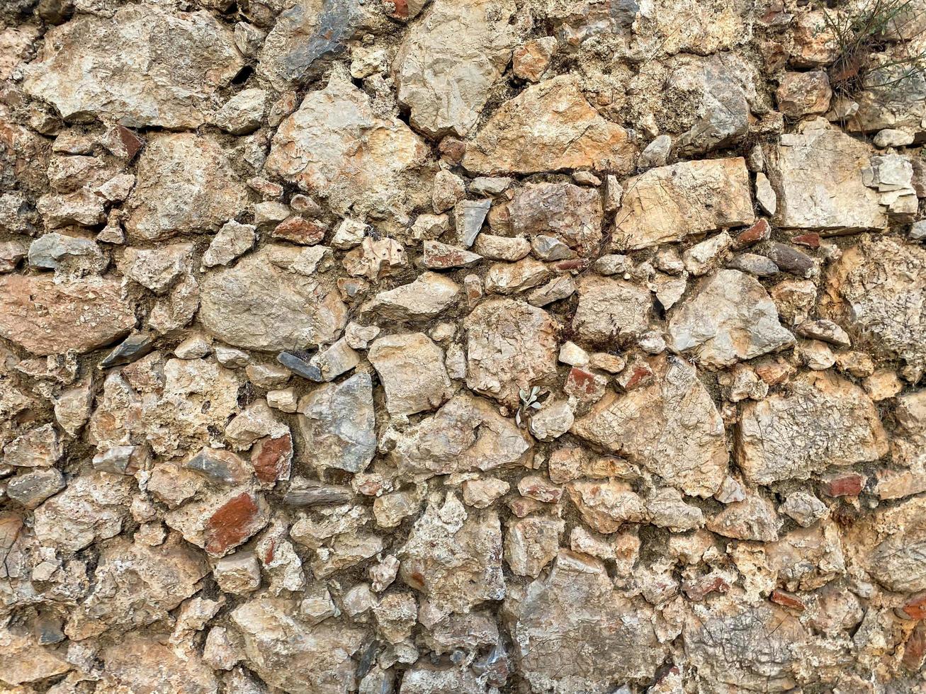 Background, texture, stone wall of round stones cobblestones bricks natural surface natural sharp convex rough stone cobblestone with cracks photo