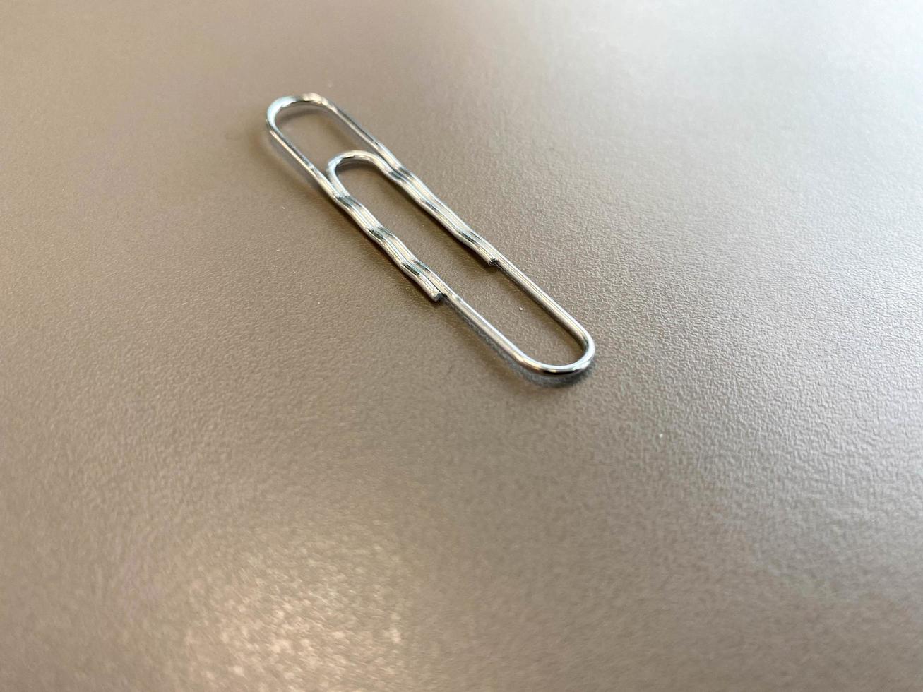 Shiny metal paper clips on a desktop with stationery in a business office. Close view photo