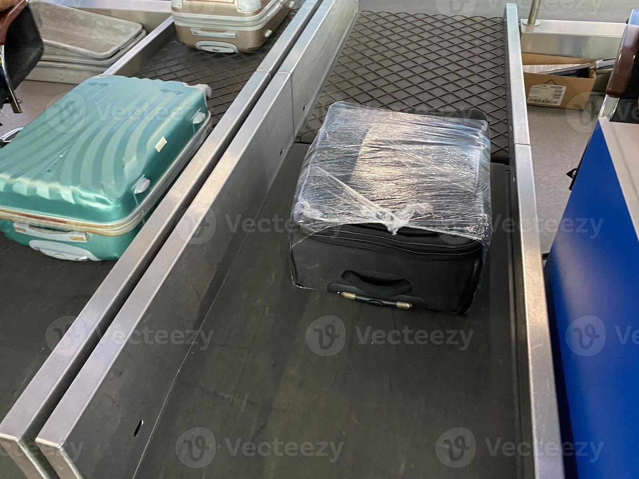 modern international airport interior view of baggage claim carousel and blue big travel bag with white sticker priority yellow label isolated on reclaim tape business air travel blurred background photo