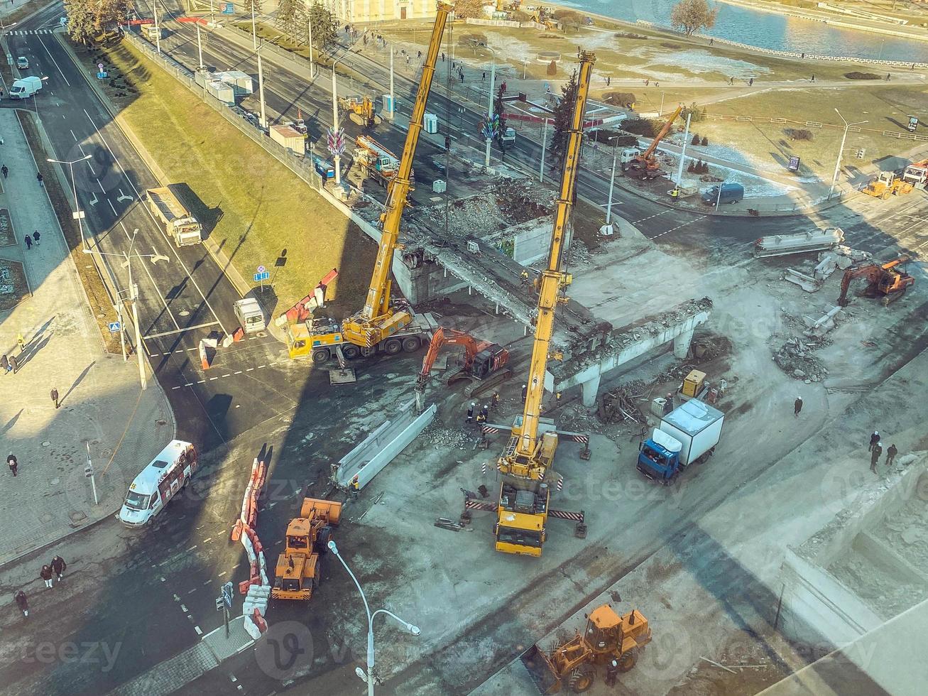 construction of a new bridge in the city center. concrete overpass. cars and construction equipment drive nearby. view from a height of the city and the construction site photo