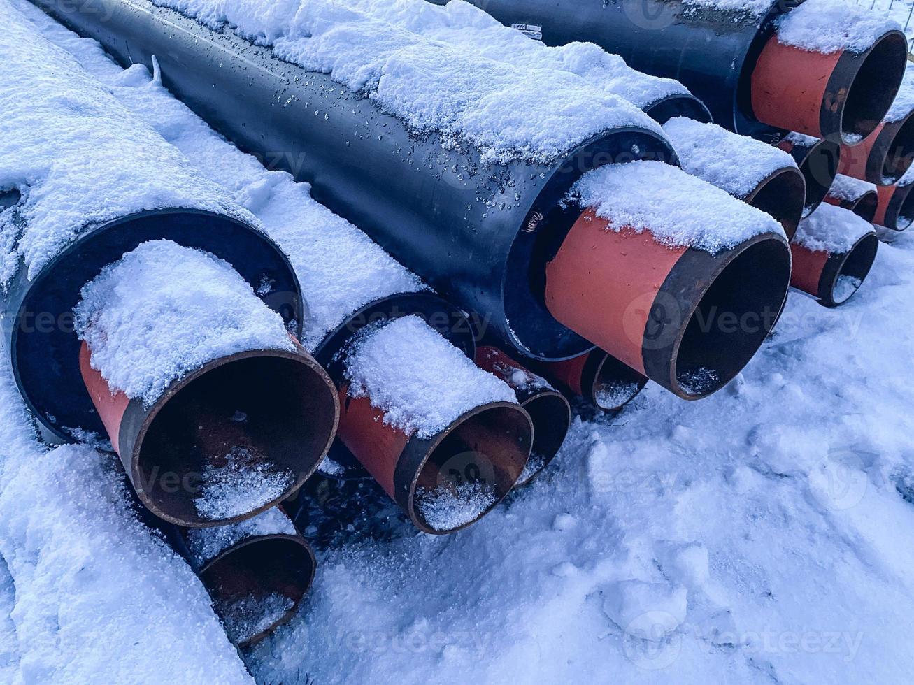 material for repair work. sewer pipes for laying communications. long, black pipes made of polypropylene on white pure snow with red tips photo