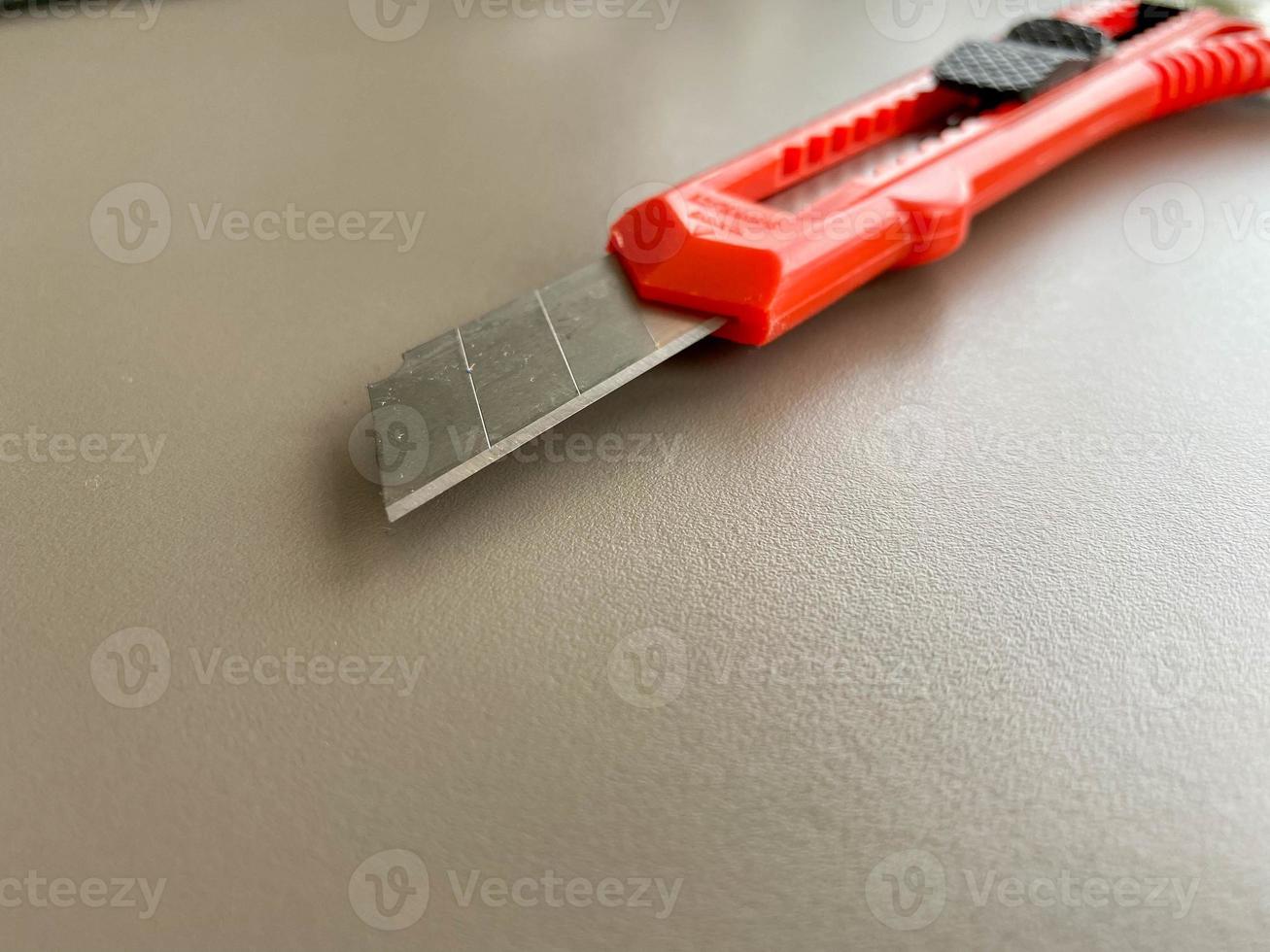 Red sharp office stationery knife with a paper cutting blade on a desktop office desk. Business work photo