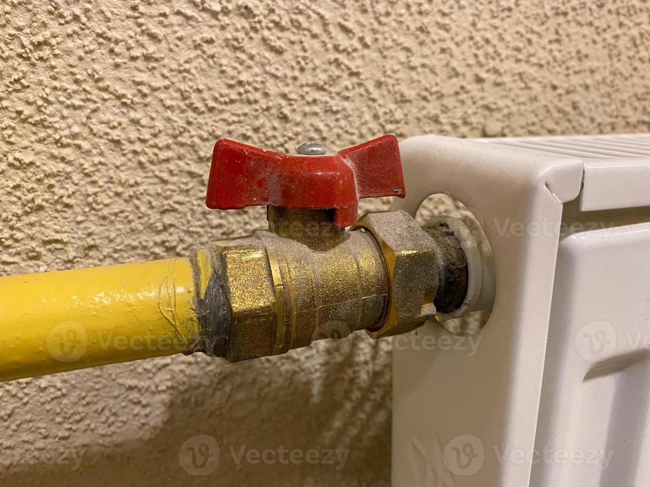 Small iron red industrial shutoff and control valves, plumbing ball valve for shutting off water and liquid flow in a metal yellow pipe photo