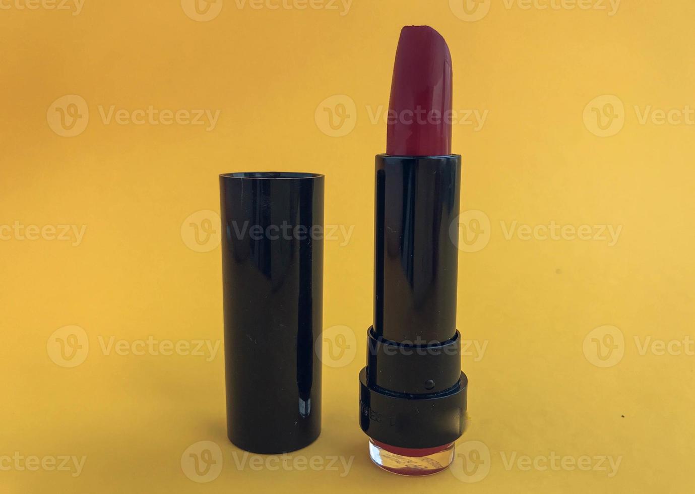 lipstick in a black compact package on a pink matte background. bright red lipstick. trendy and juicy shade for the lips of the girl. creating a glossy finish on the lips photo