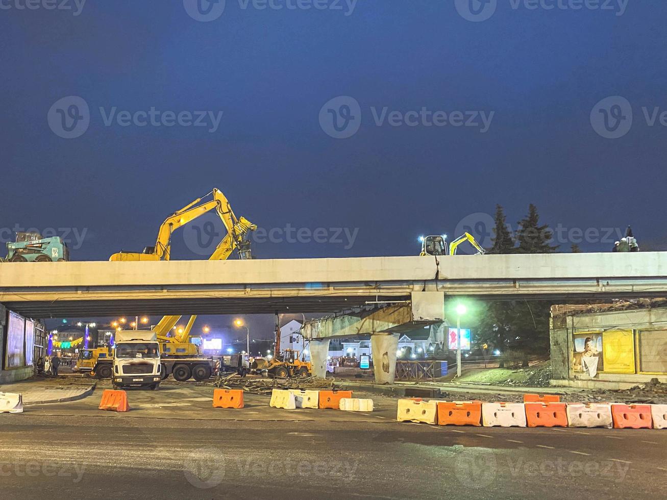 construcción de un puente en el centro de la ciudad. el camino está cercado con elementos de protección de los automóviles. el paso elevado se agrietó y está siendo reparado por la noche foto