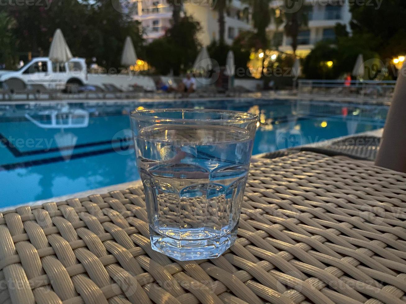 un vaso con una deliciosa bebida alcohólica clara frente a la piscina por la noche de vacaciones en un resort tropical en el hotel foto