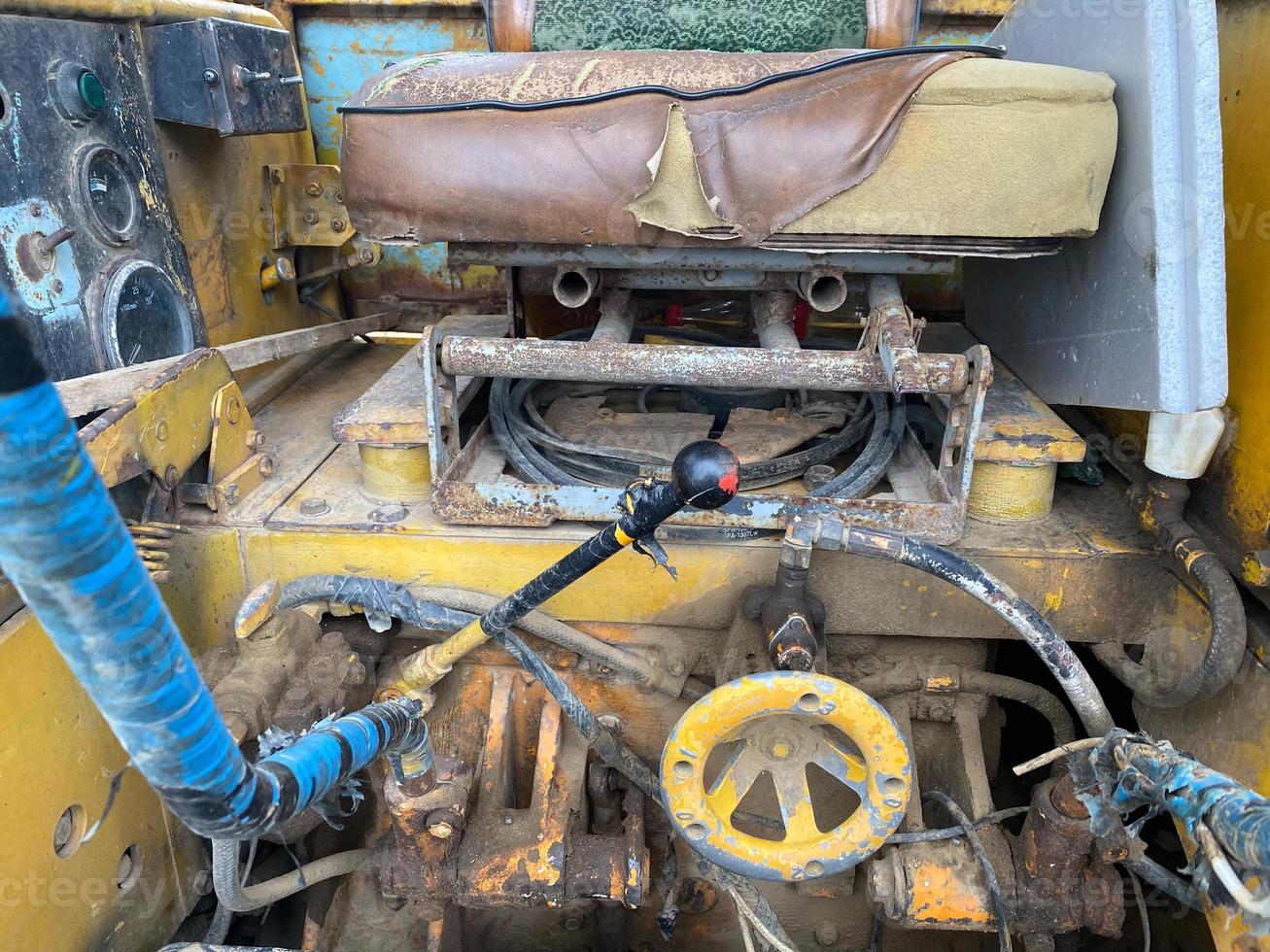 asiento, palancas y controles de un viejo rodillo de carretera amarillo para pavimentación de asfalto y reparación de carreteras en un sitio de construcción. maquinaria de construcción foto