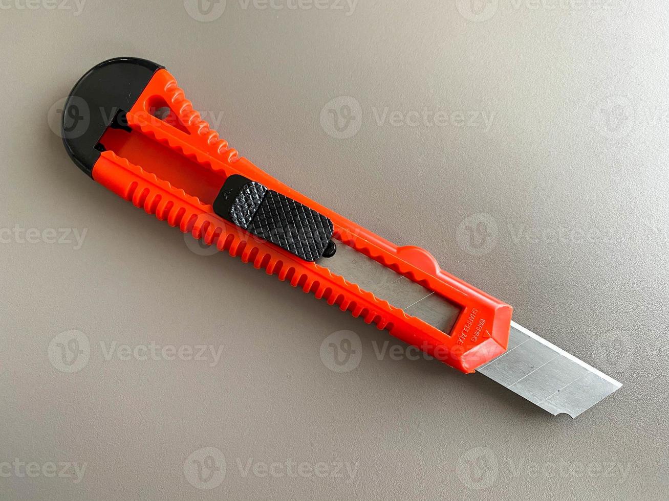 Red sharp office stationery knife with a paper cutting blade on a desktop office desk. Business work photo