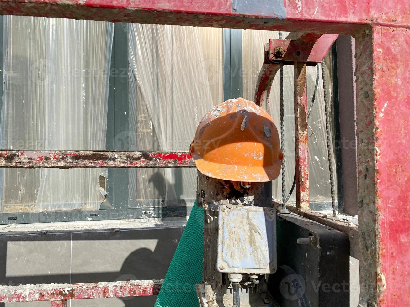 Yellow plastic protective dirty scratched old construction worker's helmet to protect head from falling objects at construction site photo