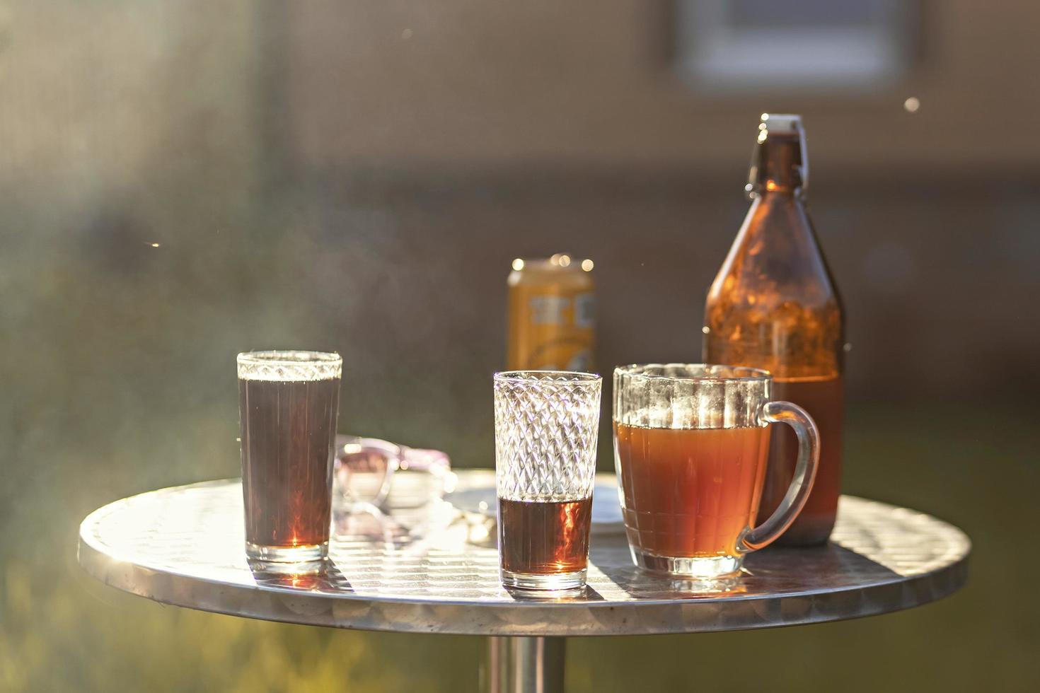 tarde de verano bebidas de colores en varios vasos en la mesa al aire libre, una fiesta en la casa del patio trasero con bebidas frías, una mesa puesta, horario de verano. foto