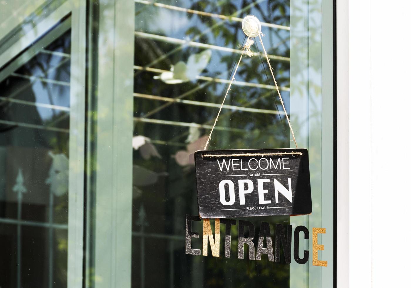 Hanging sign with message WELCOME OPEN on glass door at coffee shop photo
