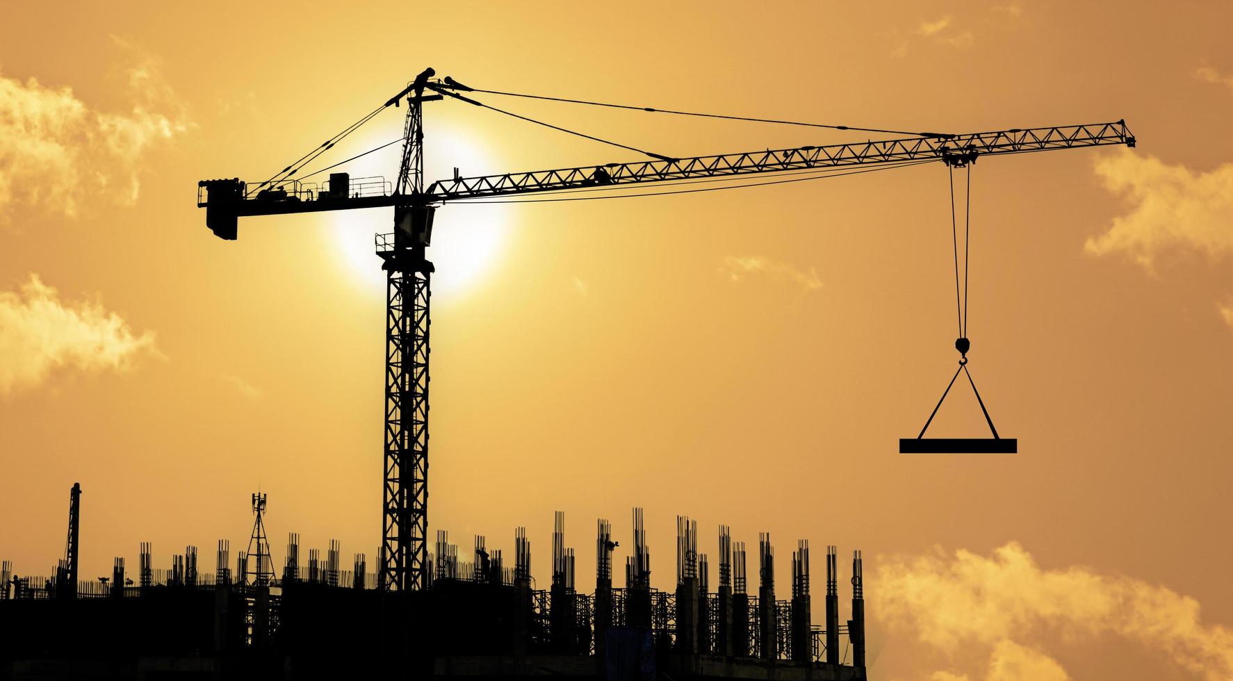 Silhouettes of tower construction cranes with yellow sky at morning time photo