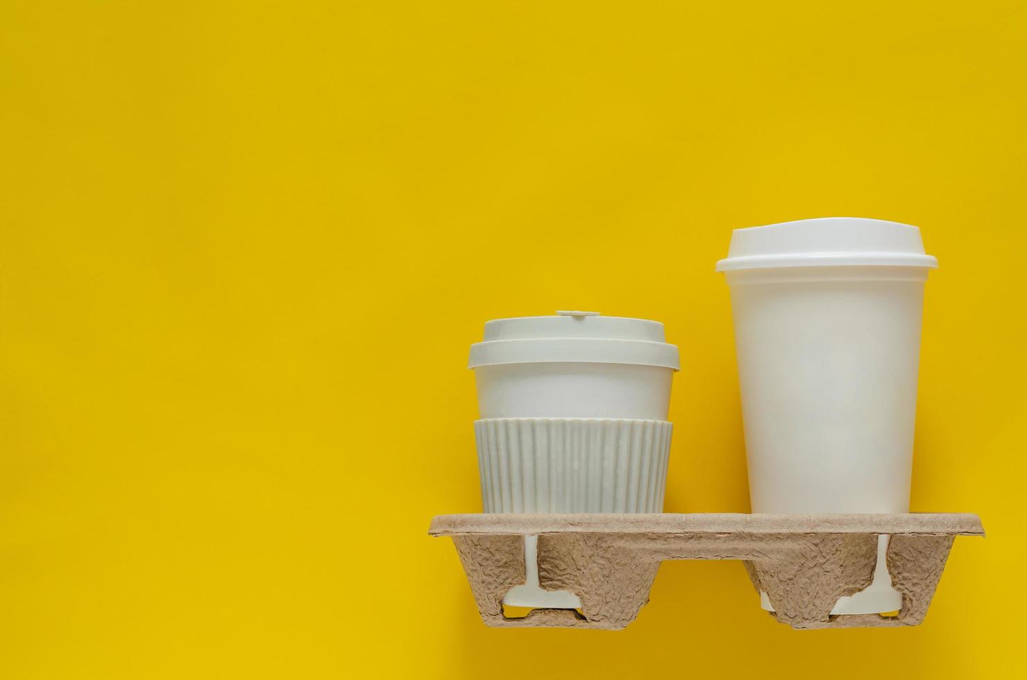 The recycle cups of coffee in reuse paper tray put on yellow paper background for World environment concept. photo