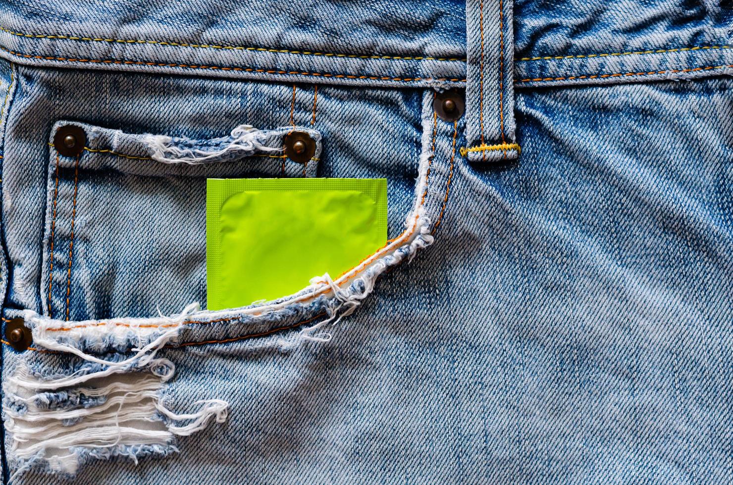 condón en el bolsillo de los jeans para el sexo seguro, la salud sexual mundial y el concepto del día del sida. foto