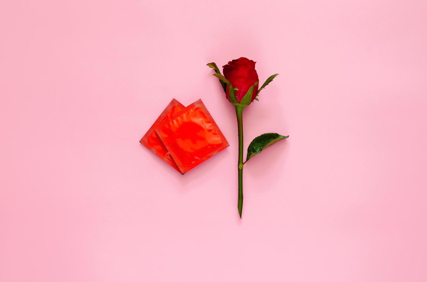 Red rose with condom package that set as love shape for minimal safe sex, world sexual health and aids day concept. photo