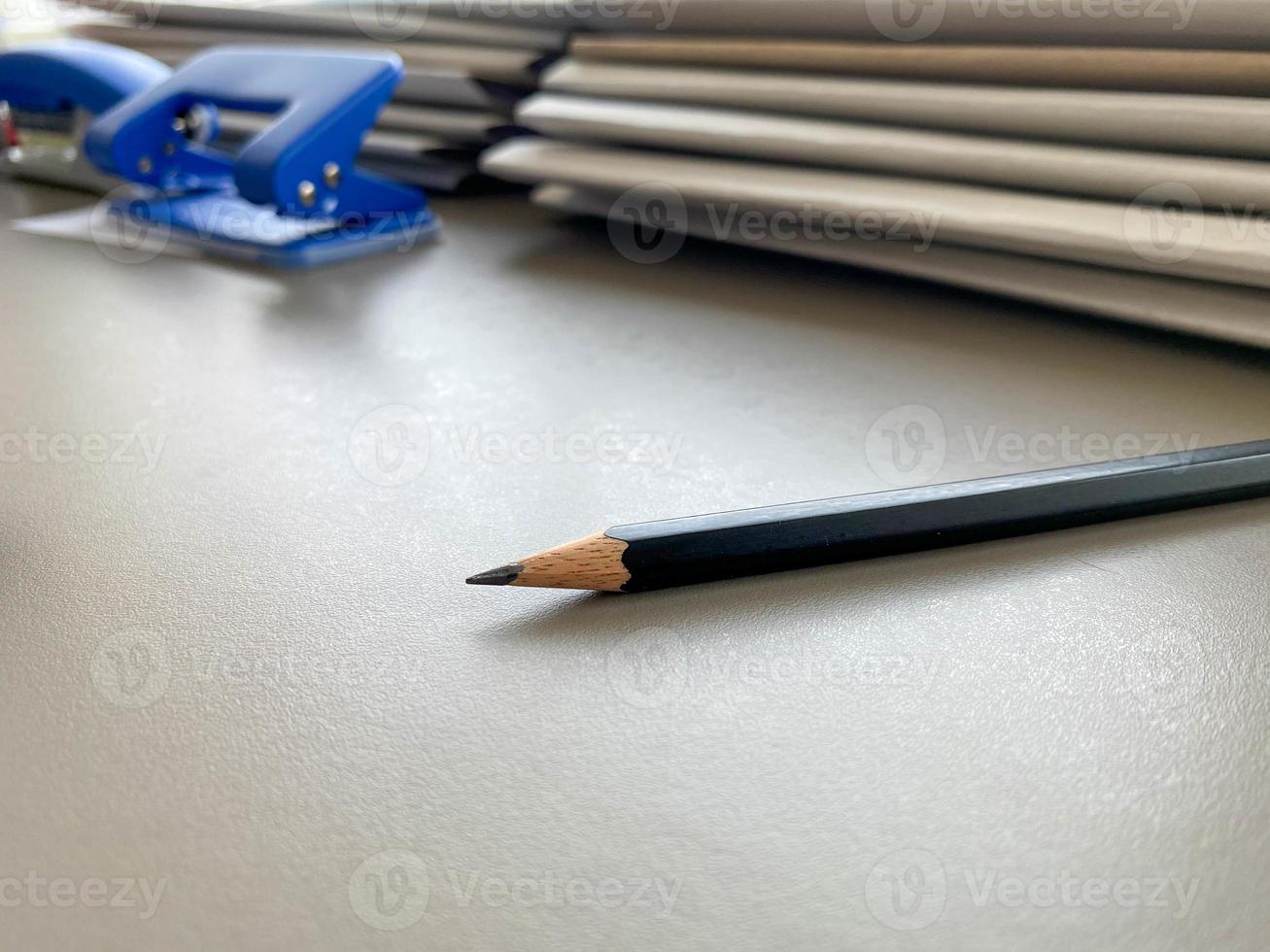 A simple black pencil lies sharply sharpened next to folders with sheets of paper and documents on the working business desk in the office. Stationery photo