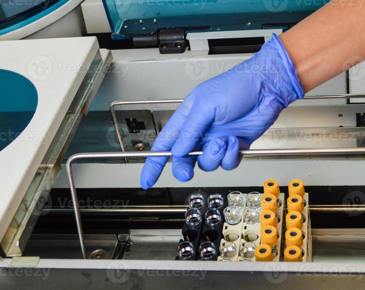 a doctor of laboratory diagnostics puts test tubes with multi-colored caps into the analyzer to perform laboratory tests. health diagnostics with the help of tests photo