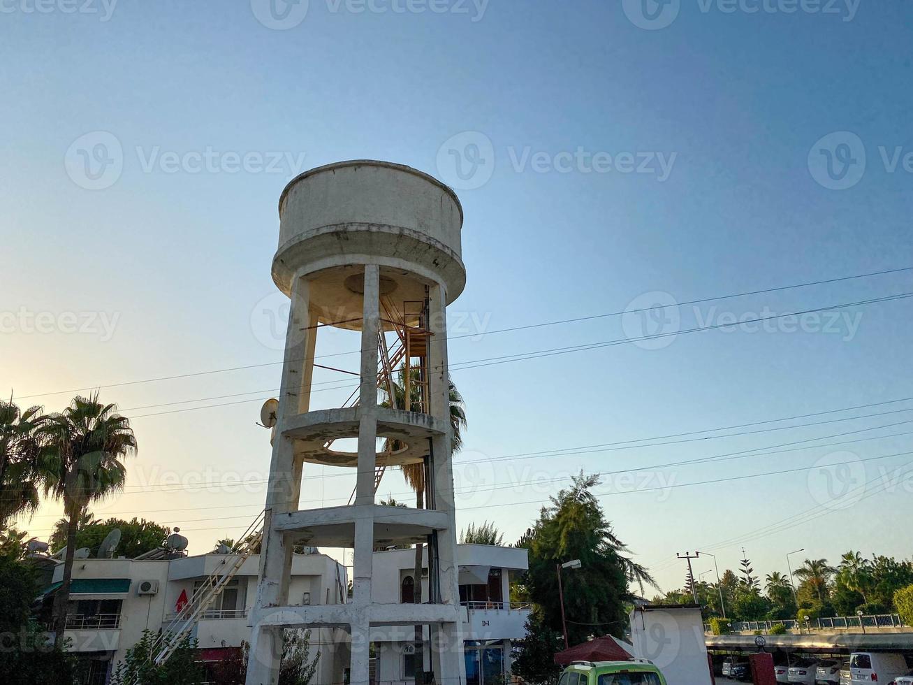 A large white water tower against the background of the sky and palm trees in a tourist warm eastern tropical country southern resort photo