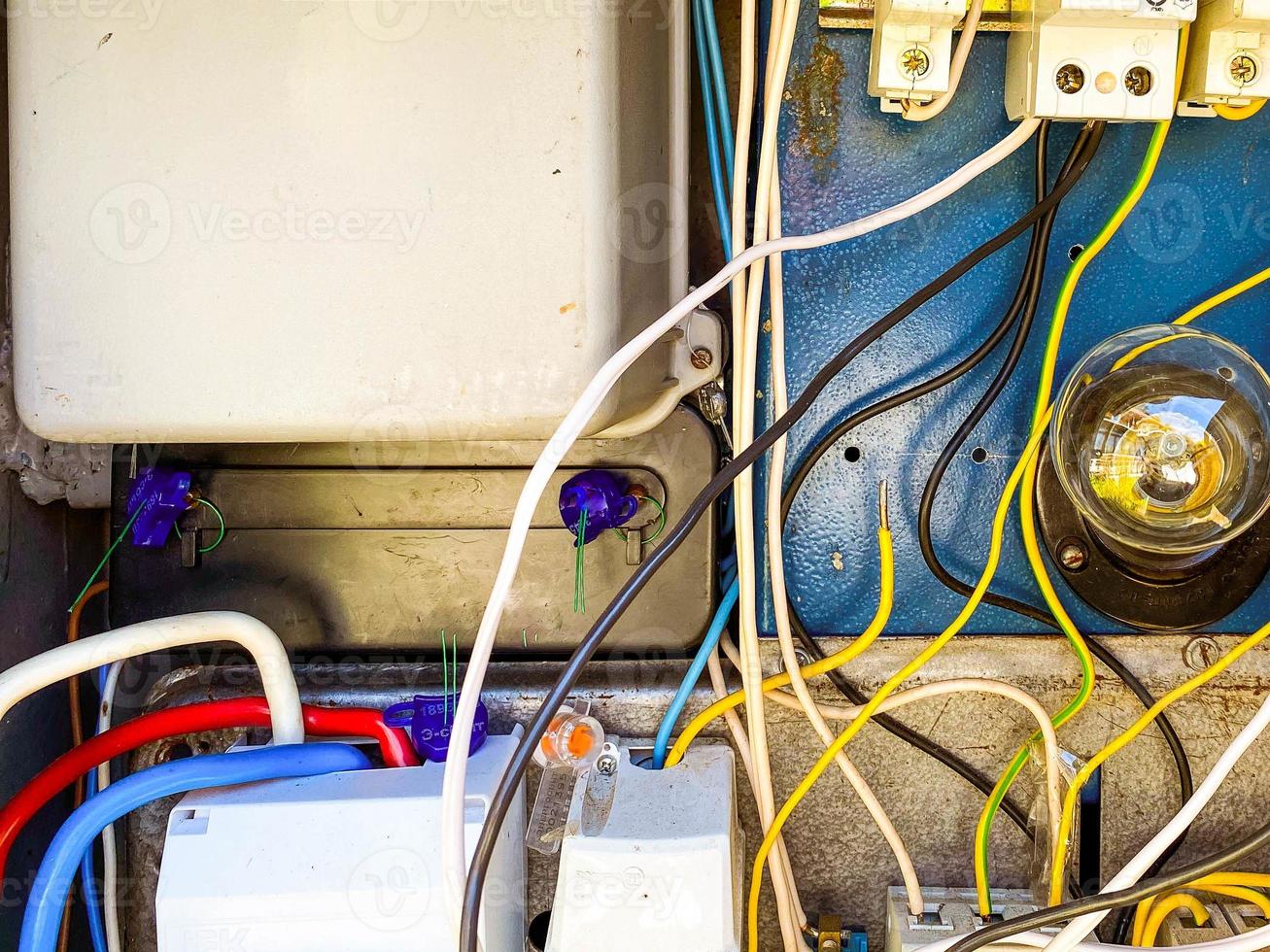 an electrical panel with many wires for conducting light to people's homes. homemade shield with a light bulb and sockets. current inside the box photo