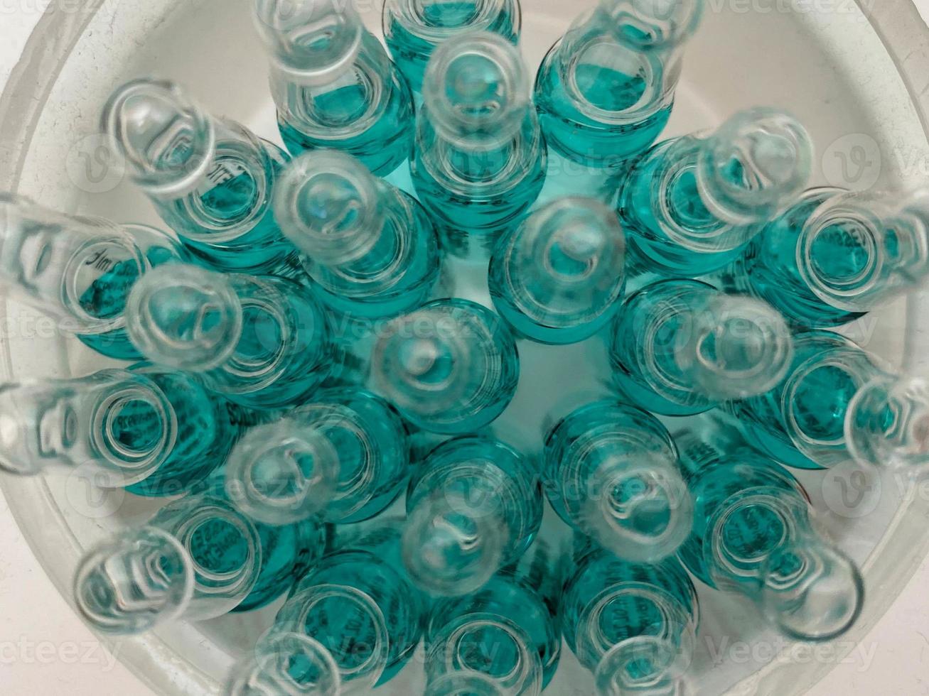 Glass medical ampoule vial for injection. Medicine is liquid sodium chloride with of aqueous solution in ampulla. Close up. Bottles ampule multicolor photo