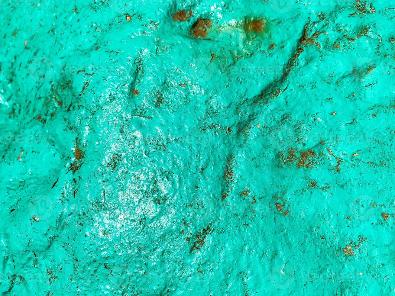 bulk paint on a piece of metal. the texture is turquoise, interspersed with rust and holes. peeling paint, cracked material. paint and metal background photo
