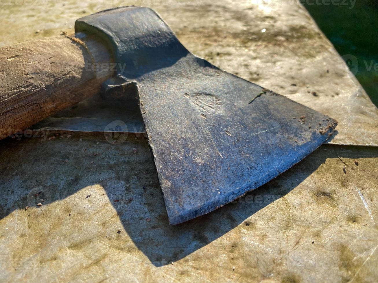 An old iron metal ax with a butt and a rusty and texture beautiful handle for chopping firewood, wood and trees lies on an iron background photo