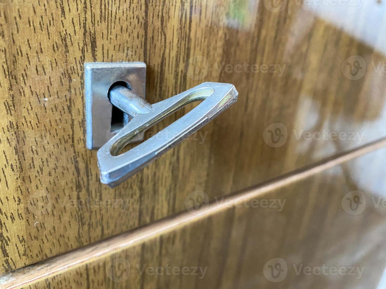 llave cromada de metal de hierro para abrir y cerrar la cerradura en el ojo de la cerradura en una puerta de madera foto