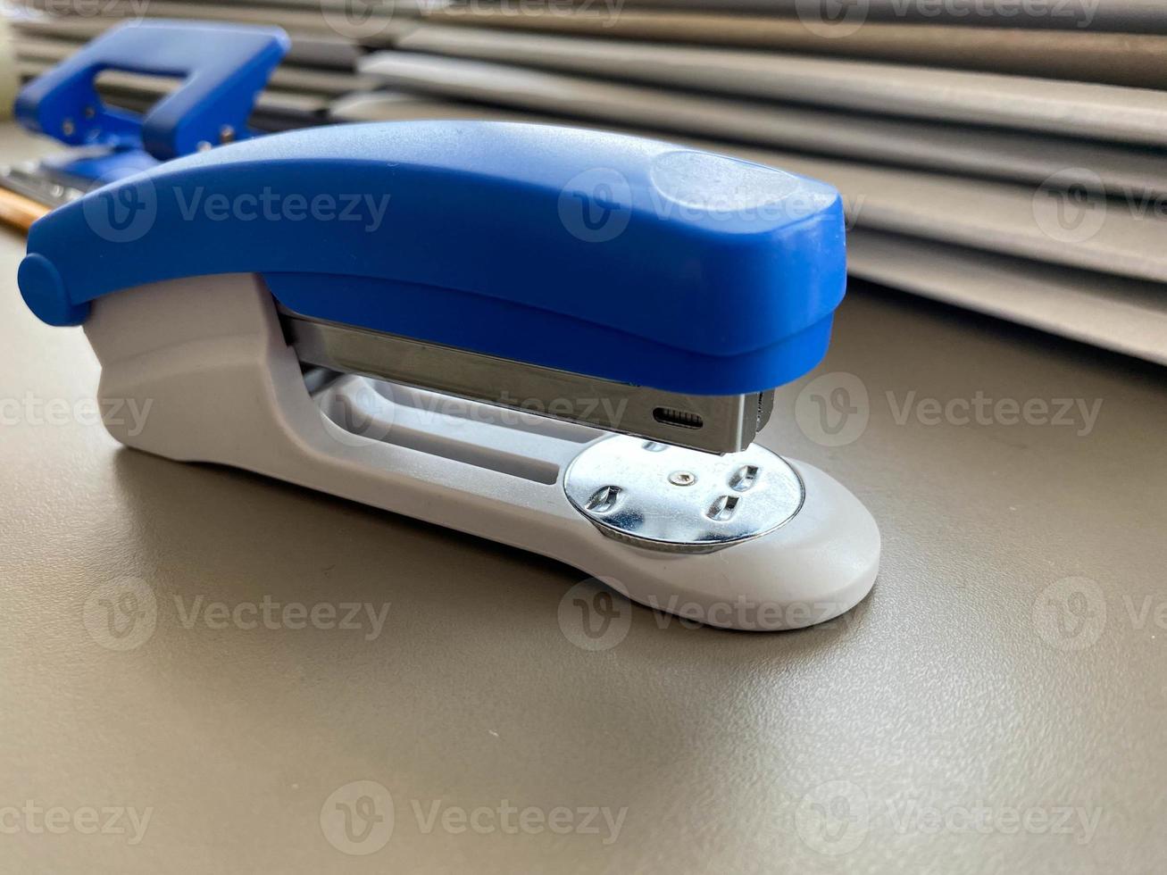 A large blue stapler for stapling paper lies next to the folders of documents on the working business desk in the office. Stationery photo