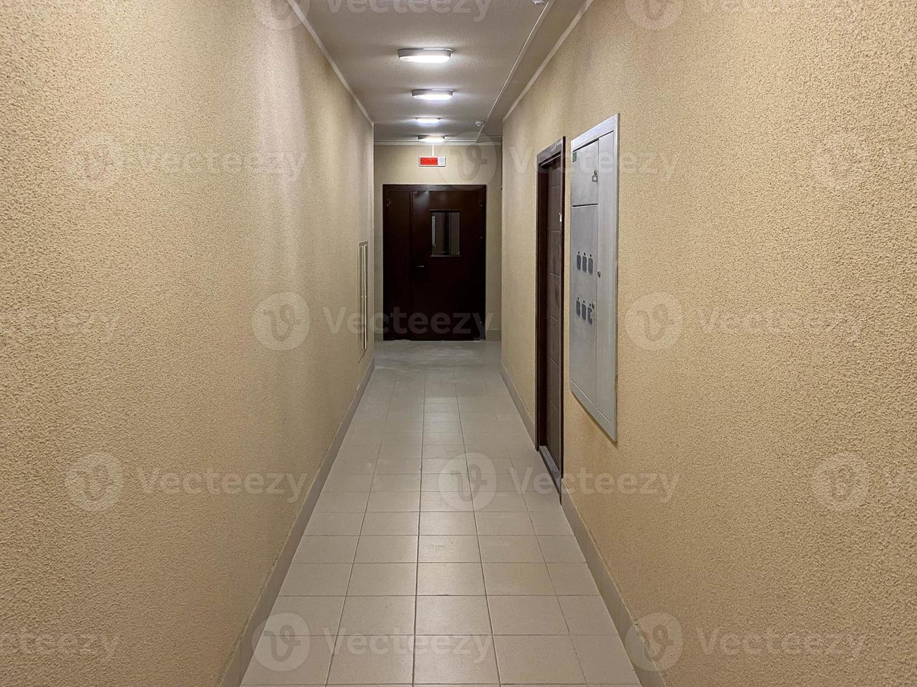 Long narrow yellow beige corridor with apartments in a new modern building photo