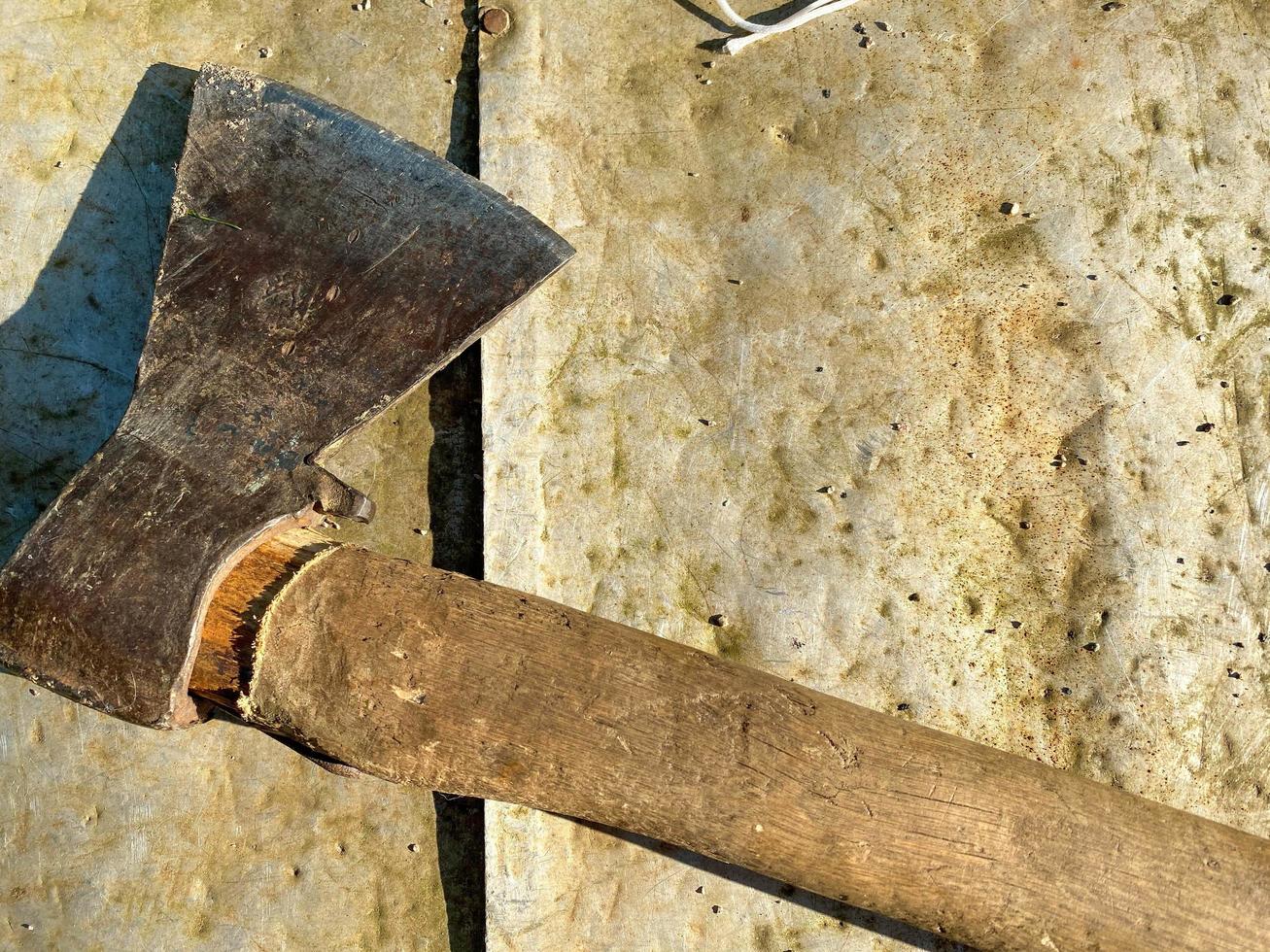 An old iron metal ax with a butt and a rusty and texture beautiful handle for chopping firewood, wood and trees lies on an iron background photo