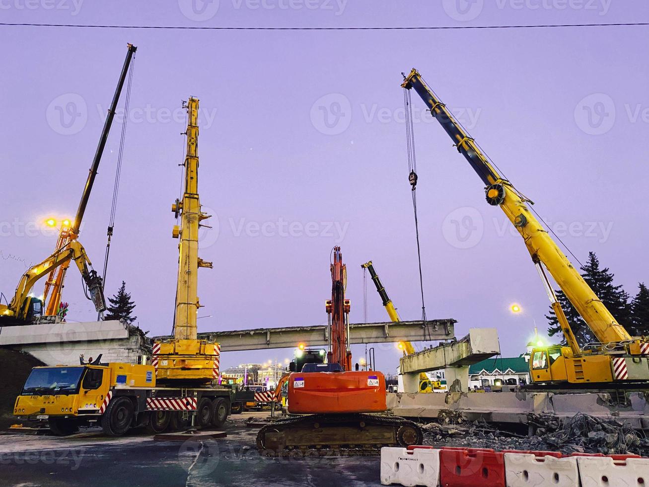 construction of a broken bridge on a busy road. construction equipment on a section of the road erects an overpass behind a plastic barrier photo