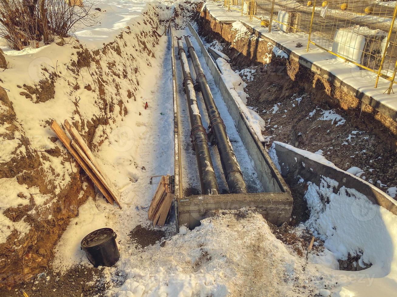 small, black, narrow pipes for laying plumbing communications. metal pipes under the snow. renovation work in a new residential area photo