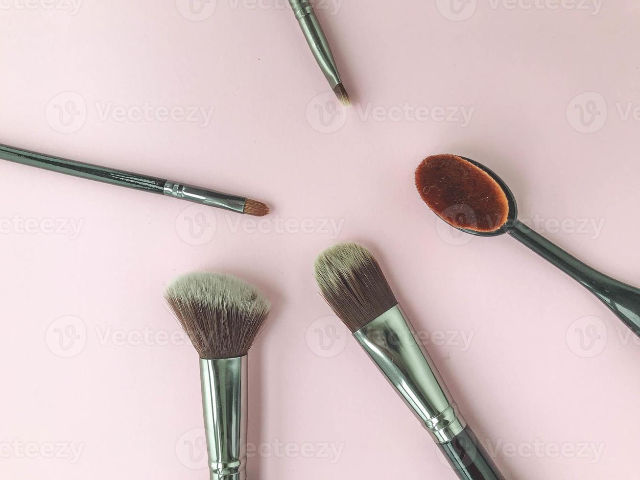 Makeup brushes and scattered face powder on bright pink background, flat lay. Space for text photo