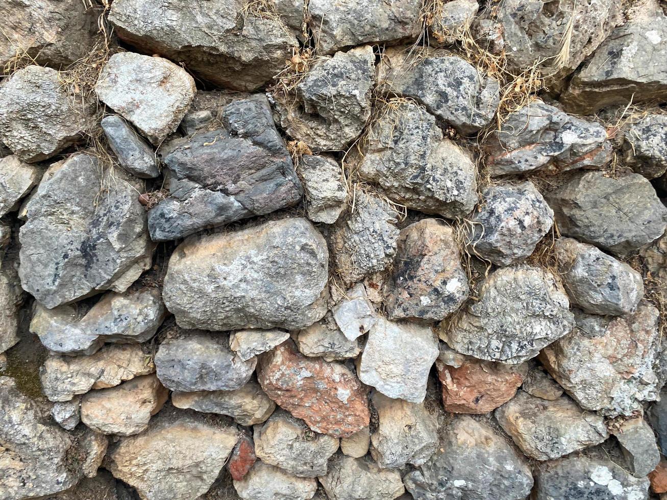 Background, texture, stone wall of round stones cobblestones bricks natural surface natural sharp convex rough stone cobblestone with cracks photo