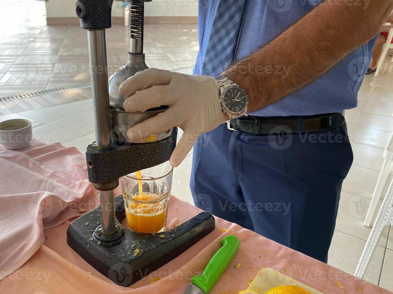 The process of making freshly squeezed yellow orange juice, a man squeezes juice into a glass with his hands in a hotel in a warm eastern tropical country southern paradise resort photo